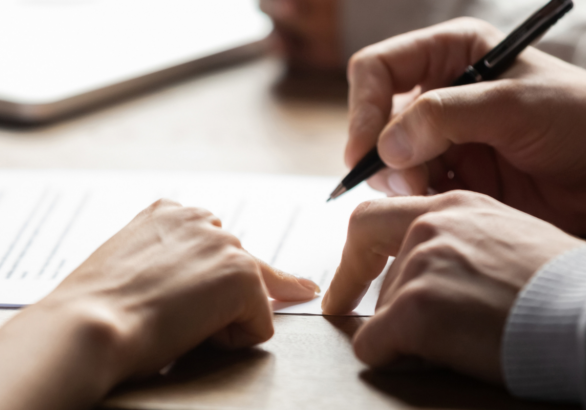 Hands signing a document on a table